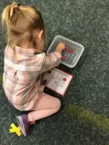 Child playing with educational activity on floor.