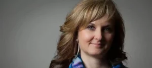 Smiling woman with wavy hair and scarf.